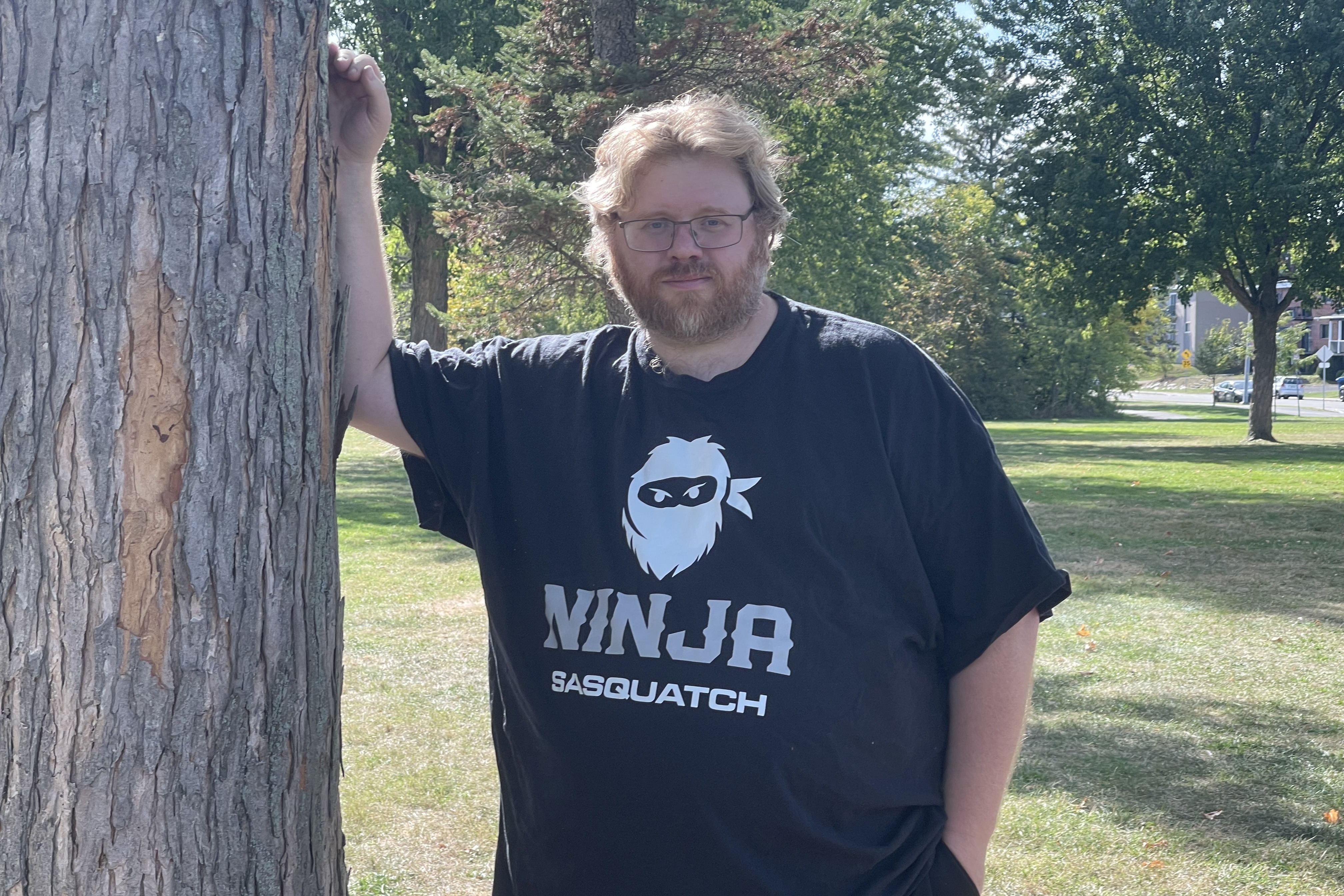 Jimmy, fondateur de Ninja Sasquatch Games, appuyé contre un tronc d'arbre en extérieur